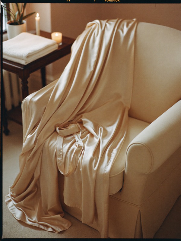 Champagne silk robe draped over a chair beside a candle — Spice Sensuality
