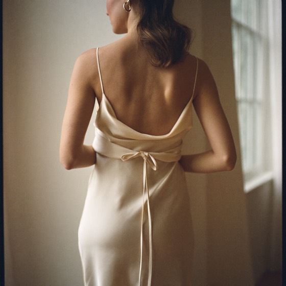 A woman in an elegant silk slip dress by a sunlit window — confidence and self-expression