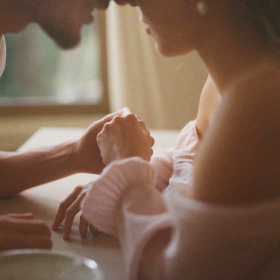 A couple holding hands in soft warm light — connection and intimacy